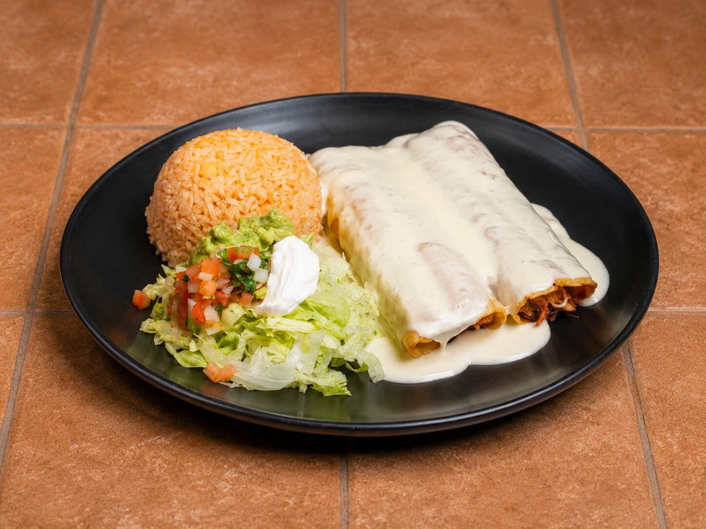 Enchiladas with melted cheese and traditional Mexican sides